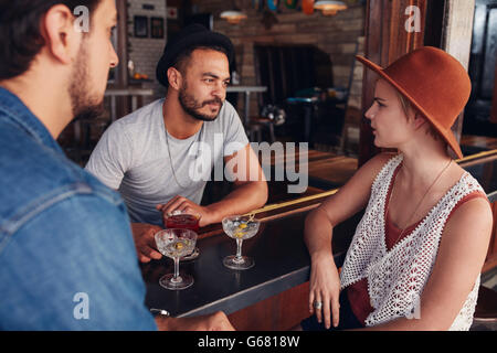 Un gruppo di giovani amici seduti e parlare in un bar. Giovani uomini e donne riuniti in un coffee shop e discutere. Foto Stock