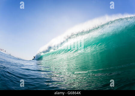 Oceano piscina d'onda all'interno di primo piano incontro di schiantarsi acqua con distante surfer surf Foto Stock