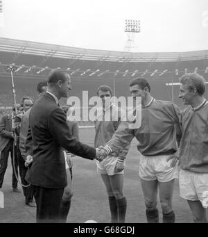 Il principe Filippo, il duca di Edimburgo, scuote le mani con Bill Foulkes, la metà centrale, mentre i giocatori del Manchester United gli furono presentati sul campo al Wembley Stadium di Londra, prima del calcio d'inizio nella fa Cup. A sinistra c'è David Herd, che doveva segnare due gol, e a destra c'è Denis Law, che doveva segnare un gol nella vittoria di United del 3-1 su Leicester City. Foto Stock