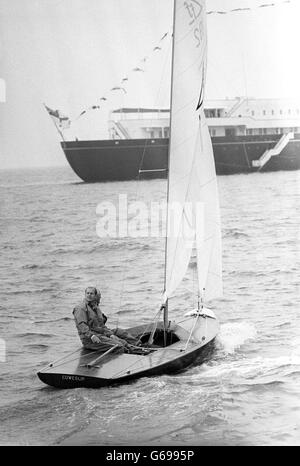 Con il Royal Yacht, Britannia sullo sfondo, il Principe Filippo, il Duca di Edimburgo e Yachtsman, Uffa Fox (nascosto dal Duca), sono mostrati a bordo della prima barca Coweslip Off Cowes, Isola di Wight, prima che Coweslip gareggesse nell'evento Flying quindici. Foto Stock