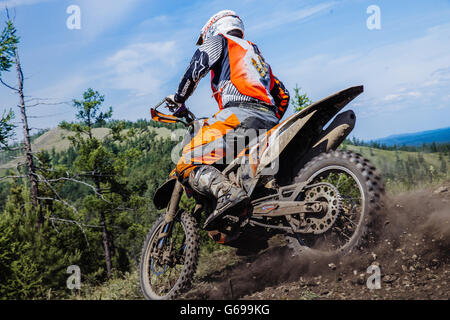 Rider andando giù per una collina, sterrato e pietre da sotto le ruote durante l'Ural Cup di Enduro Foto Stock