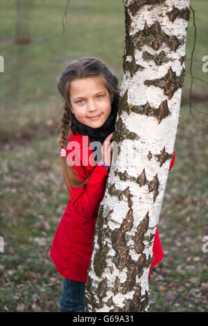 Ragazza nascosta dietro la betulla stelo Foto Stock