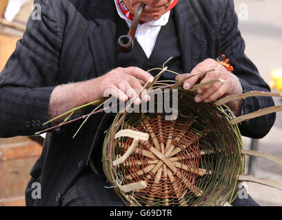 Senior uomo fumare la pipa crea un cesto di paglia Foto Stock