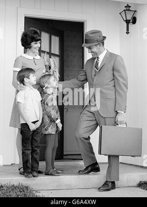 Negli anni sessanta la famiglia permanente sulla parte anteriore passi padre valigetta porta dicendo addio andando al lavoro Foto Stock