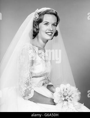 Anni sessanta ritratto donna sorridente sposa abito in pizzo NET VELO HOLDING BOUQUET nuziale Foto Stock