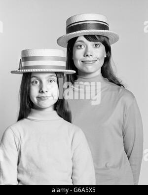 Anni Settanta MADRE E FIGLIA ritratto si assomigliano stupida espressione facciale diportista più paglia cappelli Foto Stock