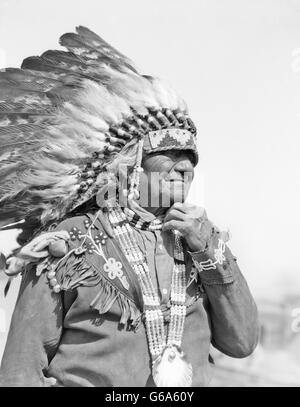 1930s Native American uomo capo indossando piena FEATHERED acconciatura di costume di perline SANTA CLARA PUEBLO NEL NUOVO MESSICO USA Foto Stock