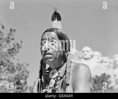 Anni Cinquanta anni sessanta nativi americani indiani Sioux uomo con il Monte Rushmore nel Sud Dakota IN BACKGROUND Foto Stock