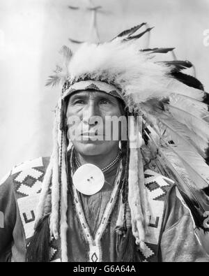 1920s ritratto Native American Indian uomo capo SEDUTA EAGLE IN PIENA COPRICAPO STONEY tribù di BANFF ALBERTA CANADA Foto Stock