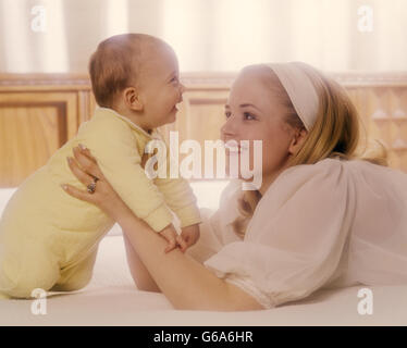 Anni Settanta donna madre IN BIANCO AZIENDA BABY IN GIALLO Foto Stock