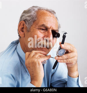 Negli anni settanta l'uomo senior di riparazione di un orologio da polso che indossa oculare di ingrandimento GUARDA LA RIPARAZIONE Foto Stock