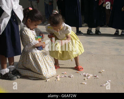 Due ragazze irachene giocano con i dolci loro dati, dai soldati britannici in una scuola primaria di villaggio vicino a Basra che si ritiene sia una delle prime a riaprirsi dopo lo scoppio della guerra. * la scuola mista si trova su una base militare abbandonata, attualmente utilizzata da migliaia di soldati britannici, e i carri armati Challenger 2 e i veicoli da combattimento Worror sono diventati luoghi di interesse familiari per i 107 alunni, tutti di età compresa tra i 6 e i 10 anni. Foto Stock