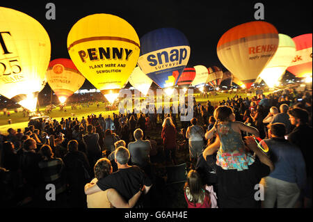 I mongolfiera si illuminano mentre sono collegati a terra durante il bagliore notturno ad Ashton Court a Bristol, come parte della Bristol International Balloon Fiesta. Foto Stock