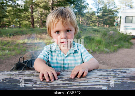 Piccolo Ragazzo seduto al tavolo da picnic, ritratto Foto Stock