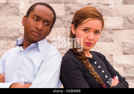 Affascinante interracial matura in posa con sconvolto le espressioni facciali, strofinando le spalle guardando nella telecamera Foto Stock