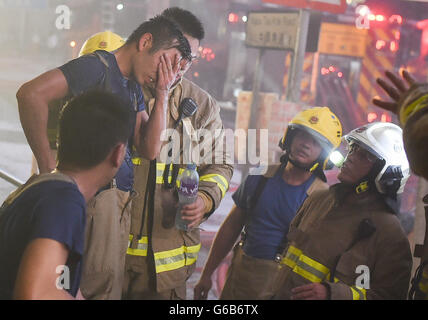 (160624) -- HONG KONG, Jun. 24, 2016 (Xinhua) -- i vigili del fuoco per prendersi una pausa da un ardente a più piani edificio industriale in Kowloon East area di Hong Kong, Cina del Sud, 23 giugno 2016. Un secondo vigile del fuoco è morto la sera di giovedì dopo aver combattuto a quattro-allarme incendio che infuria per più di due giorni in un edificio industriale di Kowloon Bay. (Xinhua/Ng Wing Kin) (Cxy) Foto Stock