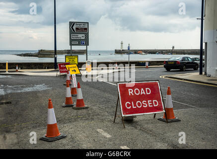 Donaghadee, County Down, Regno Unito 24 Giugno 2016 lavori stradali Segnaletica e cartelli con Donaghadee faro e porto in background le riparazioni delle superfici stradali come parte della sfera pubblica investimento Jeffrey Argenti/Alamy Live News Foto Stock