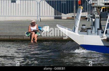 Berlino, Germania. Il 24 giugno 2016. Una donna il raffreddamento i suoi piedi nel fiume Spree mentre una nave passa a Berlino, Germania, 24 giugno 2016. Foto: PAOLO ZINKEN/dpa/Alamy Live News Foto Stock