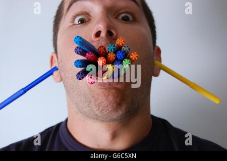 Un uomo mangiare penne colorate Foto Stock