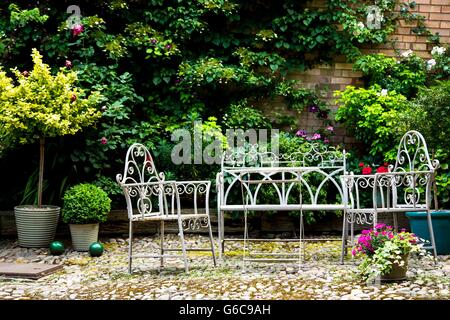 Al fresco bianco ferro battuto cubettatura tavolo e sedie nel cortile Foto Stock