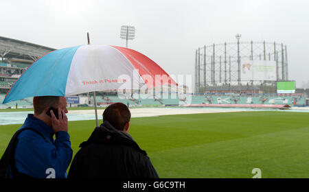 Due tifosi prendono riparo sotto un ombrello come coperte di pioggia si trovano in campo il giorno quattro della quinta prova Ashes al Kia Oval Foto Stock