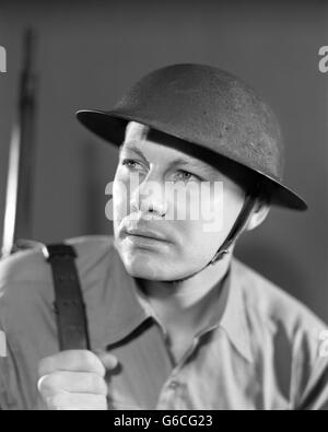 1930s 1940s grave ritratto soldato americano in uniforme che indossa BRODIE casco utilizzato dalla US Army attraverso 1942 Foto Stock