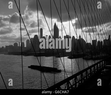 Anni Cinquanta anni sessanta DOWNTOWN skyline di Manhattan dal ponte di Brooklyn BARGE IN EAST RIVER NEW YORK STATI UNITI D'AMERICA Foto Stock