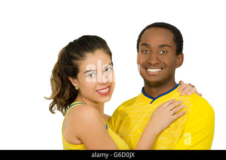 Affascinante coppia interraziale giallo da indossare magliette da calcio, abbracciando friendly in posa per la telecamera, bianco di sfondo per studio Foto Stock