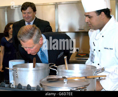 Il Principe di Galles durante la sua visita a Noon Products a Southall. Vestito con un abito a righe con una camicia a righe e cravatta blu pallido, il principe rise e scherzò con gli chef nella cucina all'avanguardia. Il principe ha assaporato l'aroma di un'iva di cottura di pollo di Achari, un curry caldo sottaceto. Foto Stock