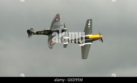 Un P-51 Mustang e Spitfire intrattengono la folla al Goodwood Revival. Foto Stock