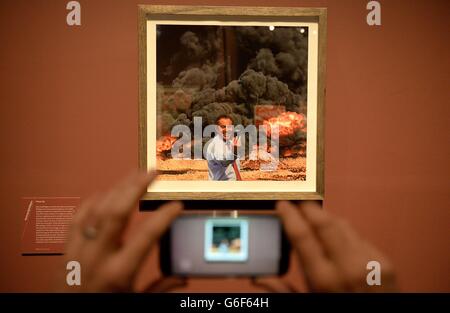 Un giornalista scatta una foto di Kennard Phillips 'Photo Op' un'immagine che raffigura l'ex primo ministro Tony Blair che ha preso un 'elfie' di fronte a un'esplosione in Iraq, durante una rassegna stampa della mostra Catalyst: Arte contemporanea e Guerra, che si svolge dal 12 ottobre 2013 al 23 febbraio 2014, presso l'IWM Nord. Foto Stock