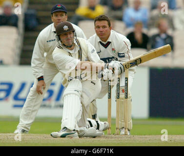 Surrey batsman Alistair Brown porta Gary Keedy del Lancashire fino al confine, mentre Warren Hegg, il guardiano del licket, guarda avanti giovedì 28 agosto 2003, durante la terza giornata della partita del campionato della contea di Frizzell tra il Lancashire e il Surrey a Old Trafford. Foto Stock