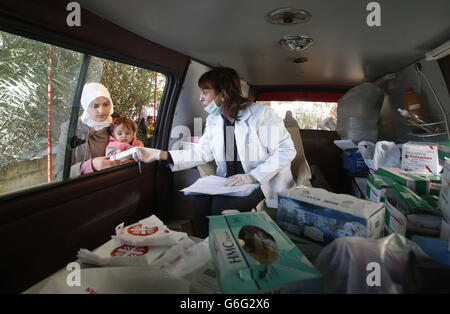 Un'infermiera fornisce medicinali ai rifugiati siriani da una clinica mobile della Caritas a Taalabaya, in Libano. Foto Stock
