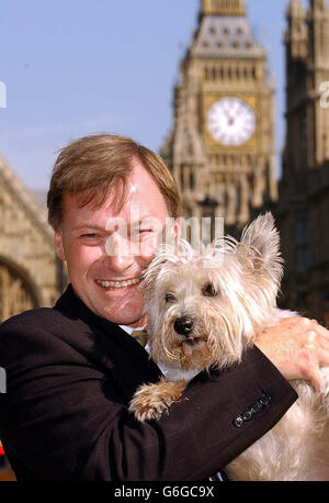 David Amess, deputato del Southend West in Essex, con un sostegno a quattro zampe al di fuori della Camera del Parlamento prima di un nuovo disegno di legge sugli animali randagi che egli propone. Il disegno di legge, approvato dalle organizzazioni per il benessere degli animali, mira ad aiutare a fermare la guerra tra vecchi proprietari e nuovi proprietari, quando gli animali randagi vengono ritrovati poi riospitati con nuovi proprietari, che a volte finiscono in battaglie e contenziosi che costano diverse migliaia di sterline per entrambe le parti. Foto Stock