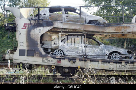 Le auto bruciate vengono ispezionate nelle vicinanze della stazione di Oxenholme vicino a Kendal. Centinaia di passeggeri del trasporto ferroviario hanno dovuto rimettiti e annullamenti dopo che un treno merci che trasportava automobili ha preso fuoco su una linea principale da Londra a Scozia. Un treno con cuccetta diretto a Londra arrivava con tre ore di ritardo e un altro con quasi due ore di ritardo. La West Coast Main Line è stata chiusa per diverse ore e alcuni dei primi treni del Nord Ovest sono stati annullati. L'incendio si trovava su un treno merci EWS che portava le automobili Citroen e Peugeot da Washwood Heath vicino a Birmingham a Bathgate a West Lothian, Scozia. Foto Stock