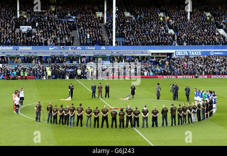 All'interno di destra i partecipanti si levano in piedi con i giocatori di Everton e Tottenham Hotspur per osservare un minuto di silenzio prima del calcio d'inizio. Foto Stock