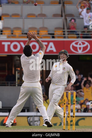 Mitchell Johnson in Australia (a sinistra) prende il pescato di James Anderson in Inghilterra dal suo bowling per vincere la partita durante il quarto giorno del primo Ashes Test al Gabba, Brisbane, Australia. Foto Stock