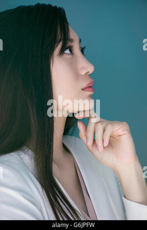 Donna fantasticando con la mano sotto il mento Foto Stock