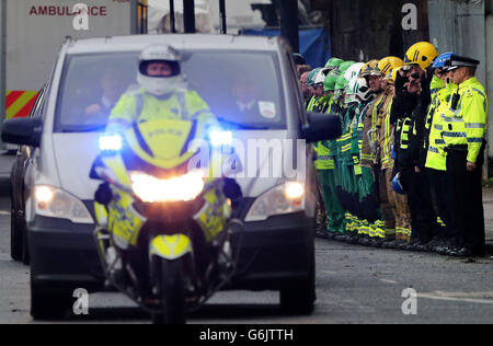 Il personale dei servizi di emergenza forma un saluto della Guardia d'onore mentre un'ambulanza privata parte portando una delle vittime dal pub Clutha Vaults a Glasgow dopo che un elicottero della polizia si è schiantato in esso il venerdì sera. Foto Stock