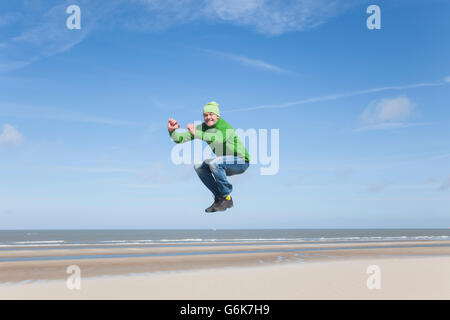 Entusiastico uomo maturo salto sulla spiaggia Foto Stock