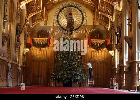David Westwood, conservatore della Royal Collection, applica il tocco finale a un albero di Natale di sei metri di Nordman Fir nella St George's Hall, che fa parte della mostra natalizia al Castello di Windsor, Berkshire. Foto Stock