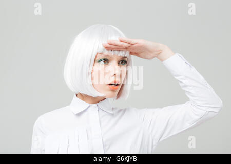 Primo piano della bella giovane donna con capelli biondi guardando lontano su sfondo bianco Foto Stock