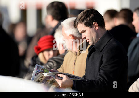 Un corridore controlla la forma nel Racing Post durante il Tingle Creek Christmas Festival a Sandown Racecourse Foto Stock