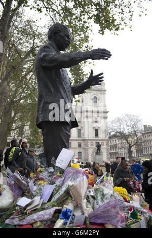 Fiori e tributi accanto alla statua di Nelson Mandela in Piazza Westminster, nel centro di Londra dopo la morte dell'ex presidente sudafricano giovedì sera. Foto Stock