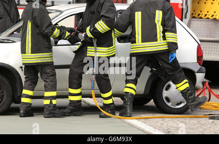 Coraggiosi vigili del fuoco alleviare un ferito dopo un incidente durante una sessione di prove per la stazione dei vigili del fuoco Foto Stock