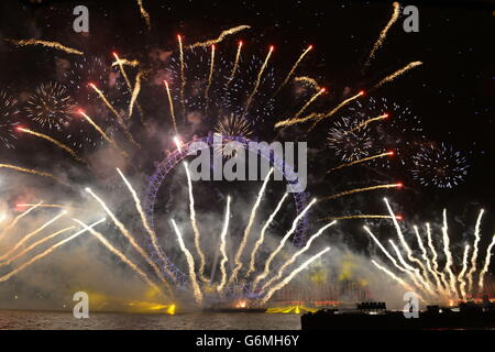 Fuochi d'artificio illuminano il cielo sopra il London Eye a Londra centrale durante i festeggiamenti di Capodanno. Foto Stock
