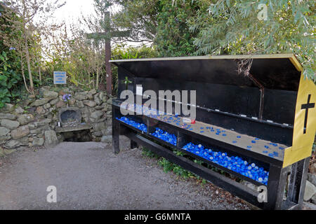 Un ambiente chiuso/coperto stand votiva per candela offre accanto a un bene sulla Nostra Signora della isola, County Wexford, Irlanda (Eire). Foto Stock