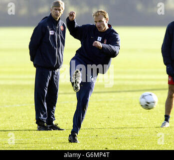 L'attaccante dell'Arsenal Dennis Bergkamp pratica il suo tiro guardato dal manager Arsene Wenger (a sinistra) durante una sessione di allenamento a London Colney, Hertfordshire, prima del gioco di domani della UEFA Champions League Group B contro Lokomotiv Moscow a Highbury. L'Arsenal ha bisogno almeno di un pareggio per garantire la qualifica al secondo turno della competizione. Foto Stock