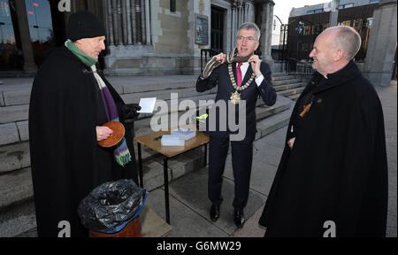 Signore Sindaco di Belfast, Mairtin o Muilleoir (centro), dopo aver fatto una donazione al Decano della Cattedrale di Sant'Anna di Belfast, don John Mann (a sinistra) con il Vescovo di Connor il Rt Rev. Alan Abernethy, Come il Dean ha iniziato un Babbo Natale nero sit-out carità vicino al sito di Venerdì bomba esplosione. Foto Stock