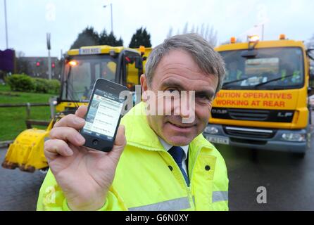 Il ministro delle strade Robert Goodwill prova la nuova app per smartphone "Fill that Hole", che consente a più ciclisti di segnalare problemi di pootole, durante la sua visita a Chadderton Way, Oldham. Foto Stock